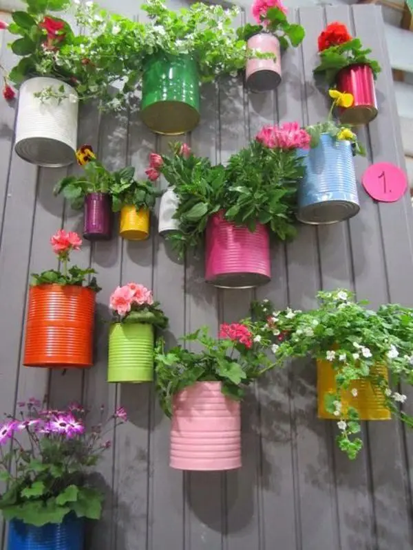 DIY vertical planters made from painted tin cans with flowers and greenery.