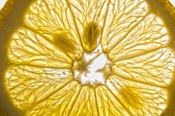 : Close-up of a fresh lemon slice glowing under light.