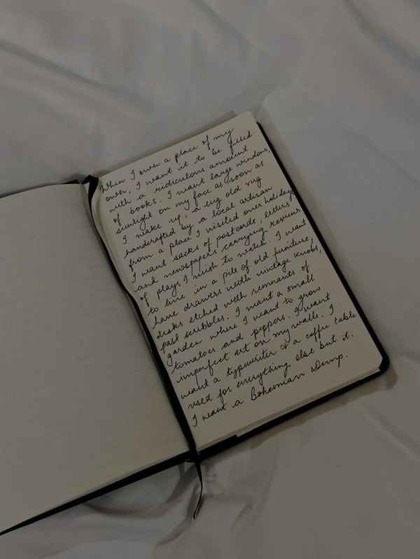 Journal with long handwritten notes lying on a white sheet.