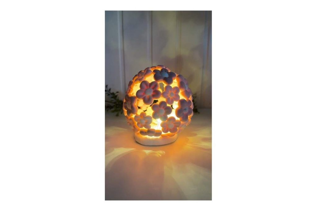 Foam clay decorative lamp designed with flower shapes, glowing with a warm yellow light on a white table.
