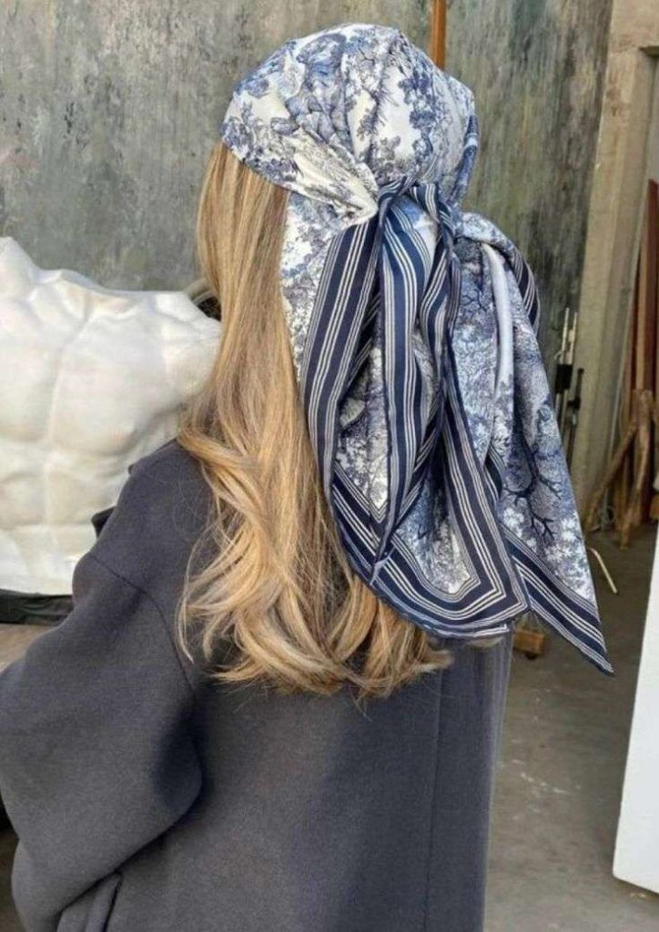 “Woman wearing a silky patterned headscarf with long tied bow detail, showcasing Spring/Summer 2026 fashion trend.”