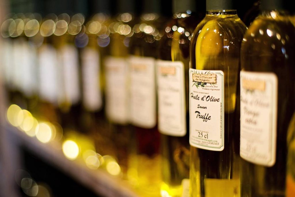Alt Text: Olive oil bottles lined up on shelf with golden glow lighting.