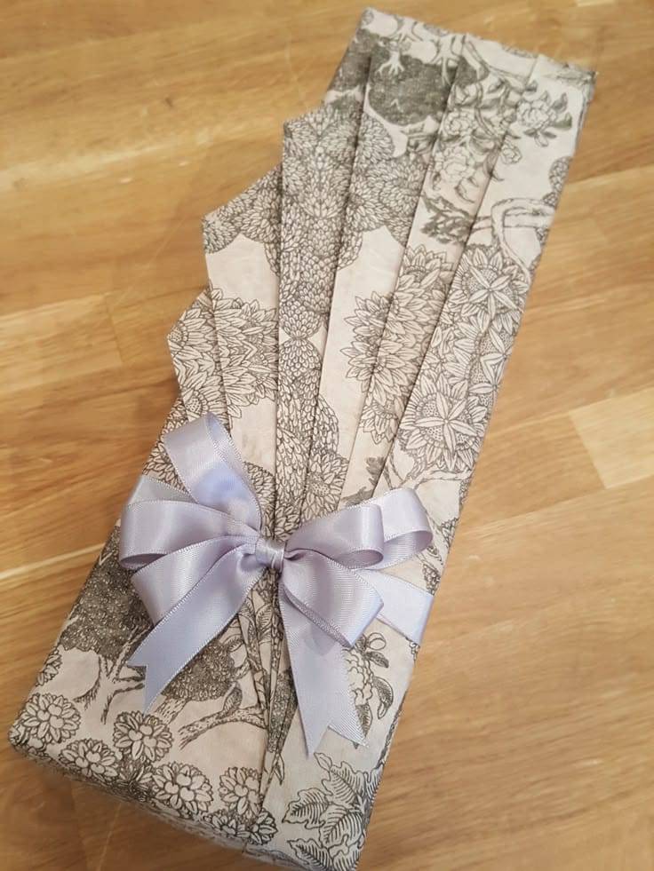 Origami-inspired gift wrapping with folded patterned paper and ribbon bow.