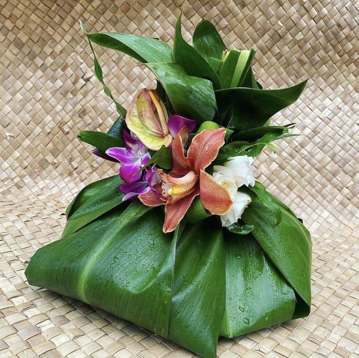 Gift wrapped in banana leaves with fresh orchids and natural greenery.