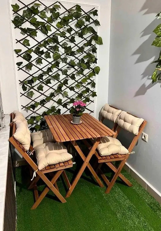 Small backyard setup with folding chairs, table, and vertical green plant wall.
