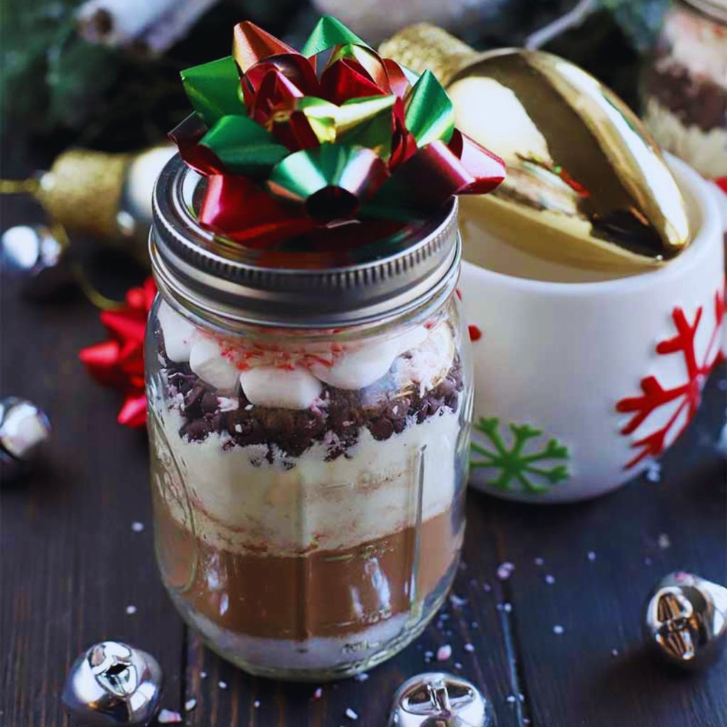 Mason jar filled with cocoa mix and marshmallows tied with a ribbon.