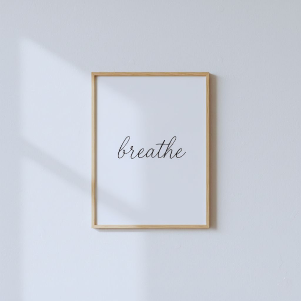 Minimalist typography wall art with the word “breathe” in cursive font on a white background.