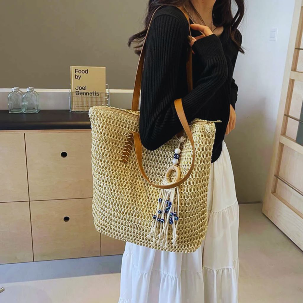 Beige handbag decorated with a navy polka dot scarf tied on the handle, surrounded by gold jewelry and perfume — elegant flat lay.
