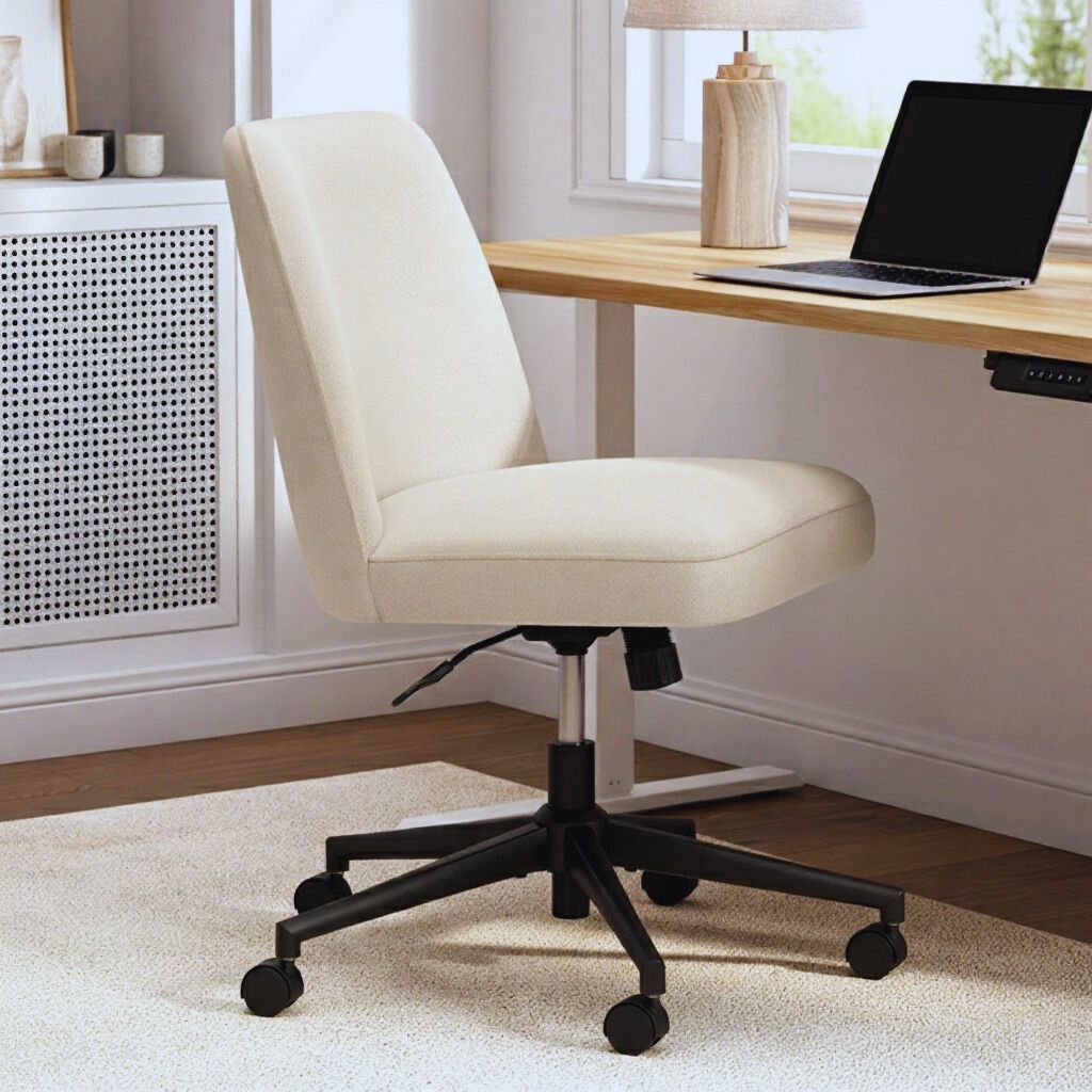 Stylish ergonomic chair in beige with cushioned seat and curved backrest, positioned at a modern home office desk with natural sunlight.