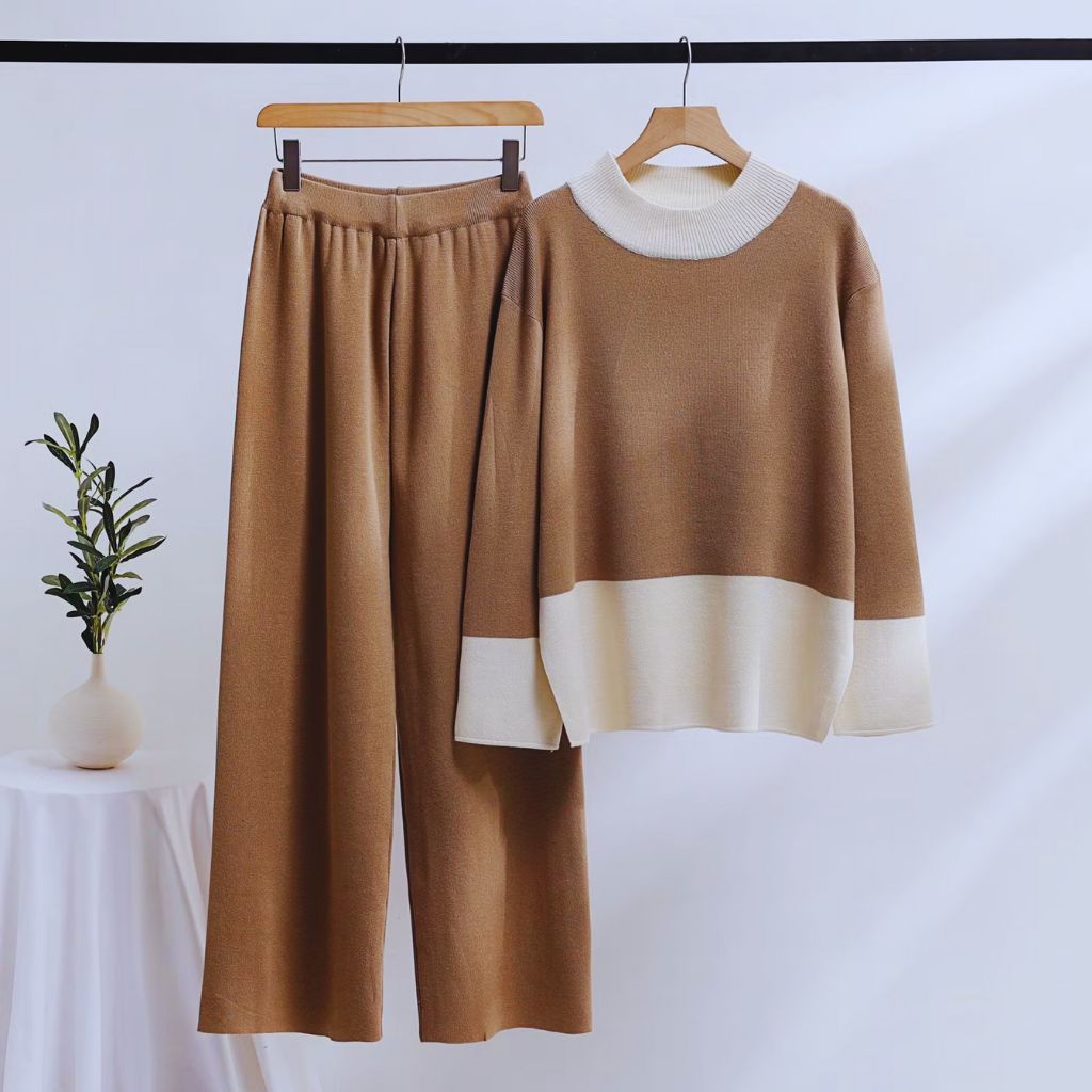 “Neutral oversized knit sweater layered over a linen shirt, styled with wide-leg trousers and a midi skirt, on a soft minimalist background.”