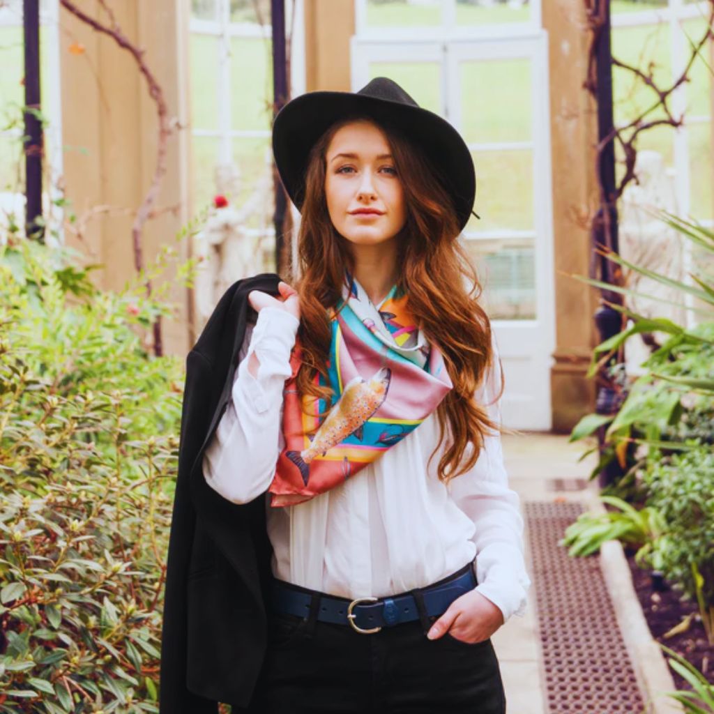 “Woman draping a silk scarf over her shoulders in a relaxed French-inspired outfit.”