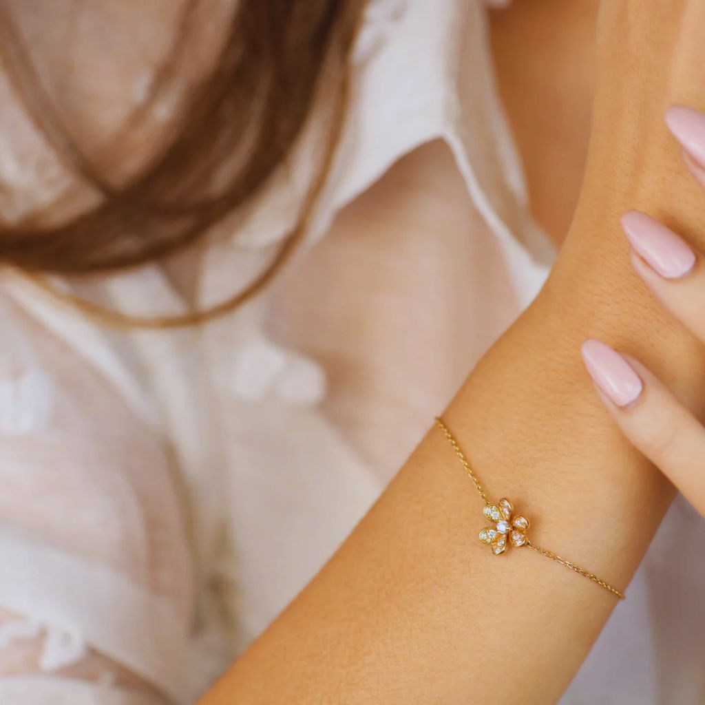 Close-up of a wrist wearing a slim gold bracelet layered with a watch for an elegant minimalist look.