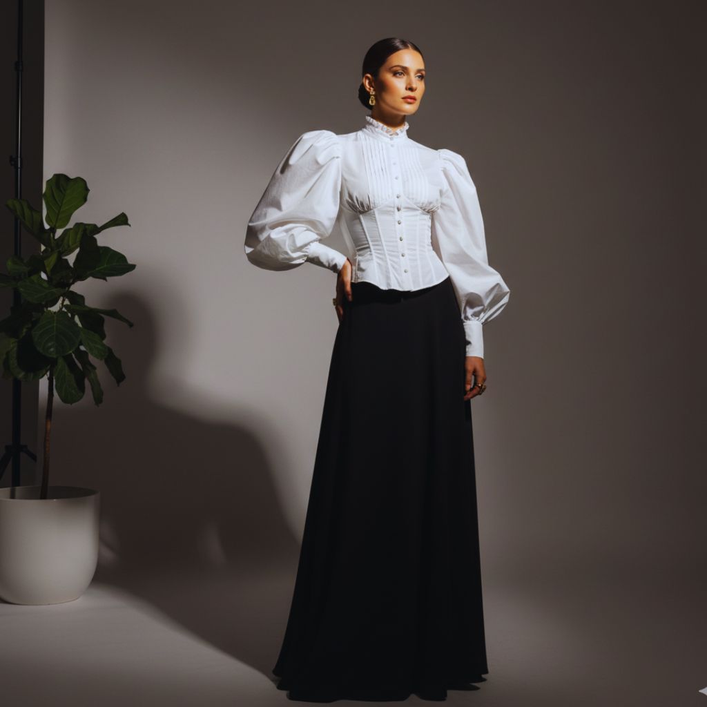 Woman in a puff-sleeve statement blouse and maxi skirt, representing bold, designer-inspired fashion.