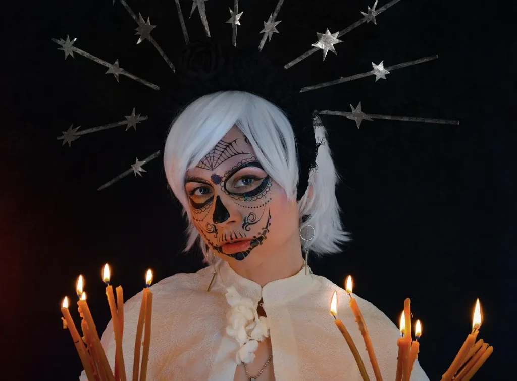 Woman with traditional sugar skull makeup and candles celebrating Día de los Muertos, the Day of the Dead”