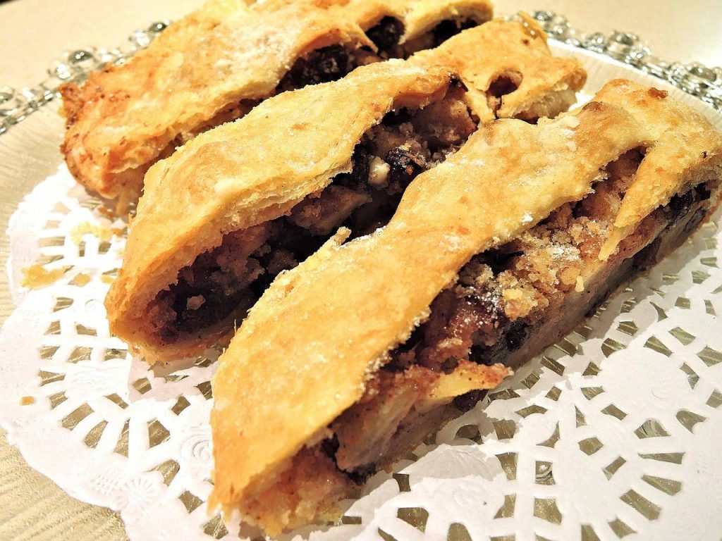 Golden flaky apple strudel slices with spiced filling on a decorative plate"