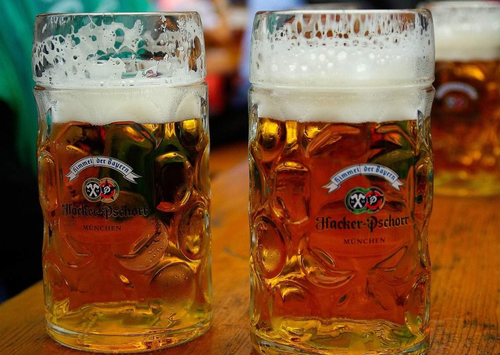"Two frothy beer steins filled with golden Oktoberfest lager on a wooden table in Munich"

