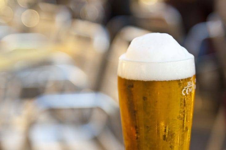 Tall pilsner glass filled with golden beer topped with a frothy foam head, perfect for Oktoberfest.