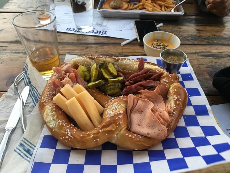 "Giant pretzel platter with cheese, meats, and pickles for Oktoberfest party"