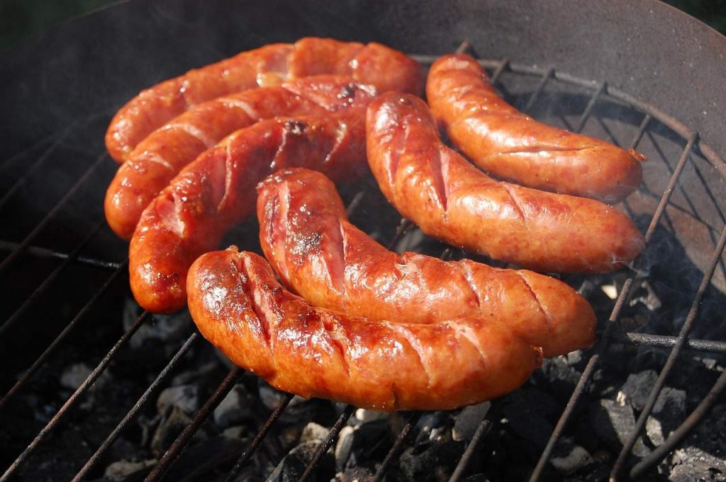 Juicy grilled German sausages sizzling on a charcoal barbecue.