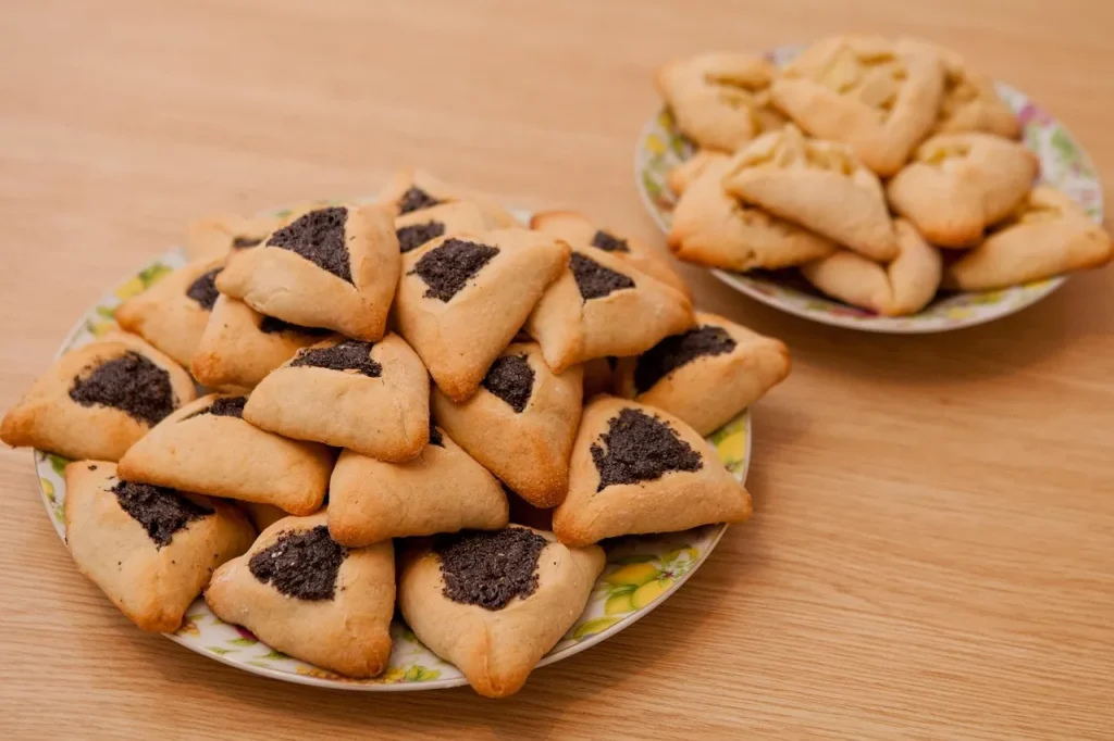 “Traditional Hamantaschen cookies served during Purim celebration, filled with poppy seed and fruit jam”