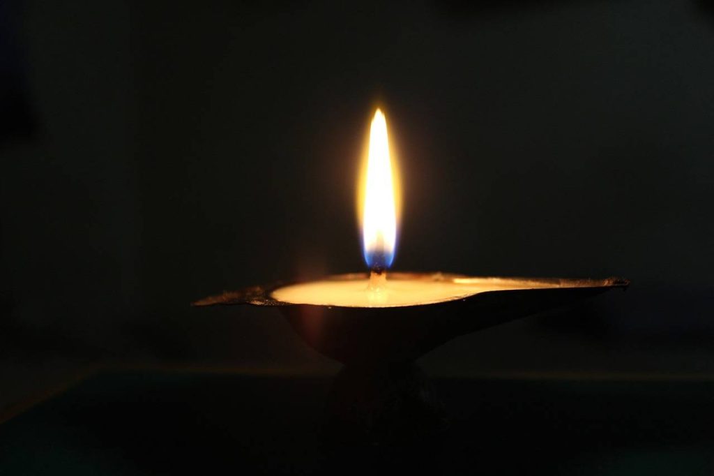 A single clay diya with a glowing flame symbolizing light and warmth during Diwali.