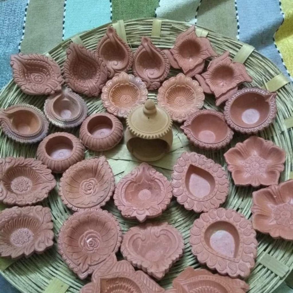 A collection of intricately designed traditional clay diyas arranged in a circular pattern on a woven tray, ready for Diwali celebrations.