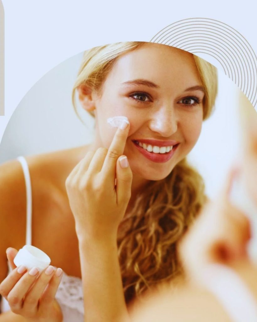 Woman applying minimal skincare routine with glowing natural skin in soft light.