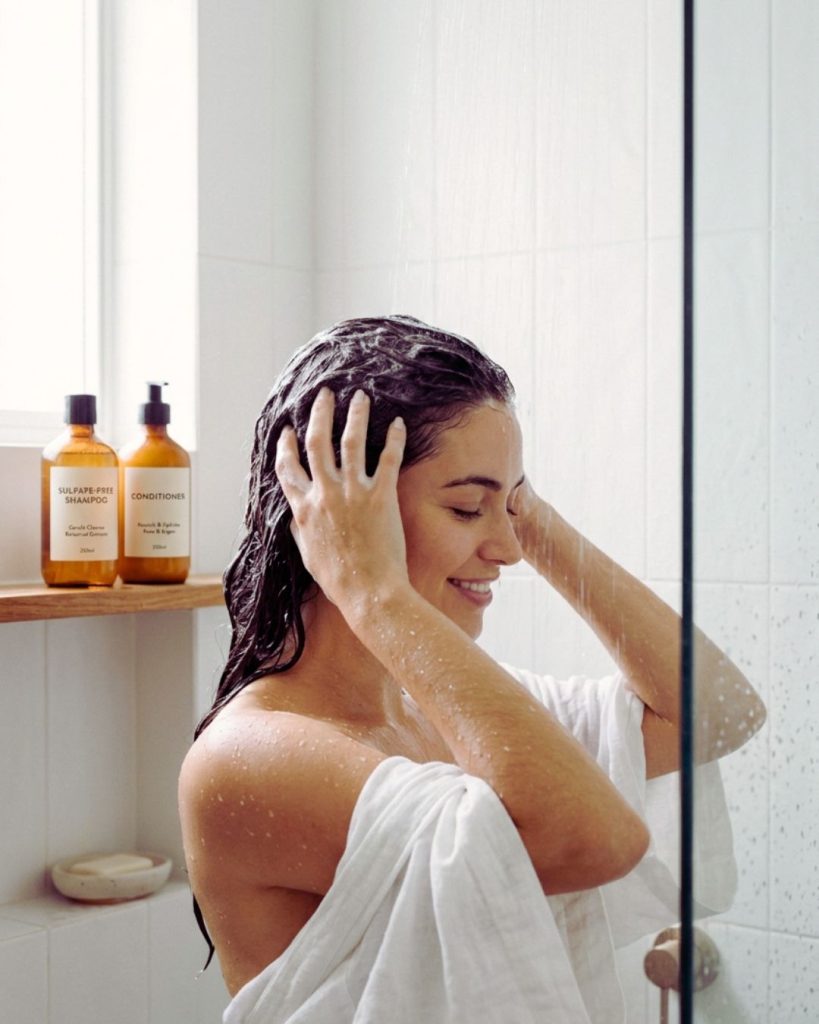 Washing curly hair with sulfate-free shampoo and detangling with conditioner for healthy hair routine.